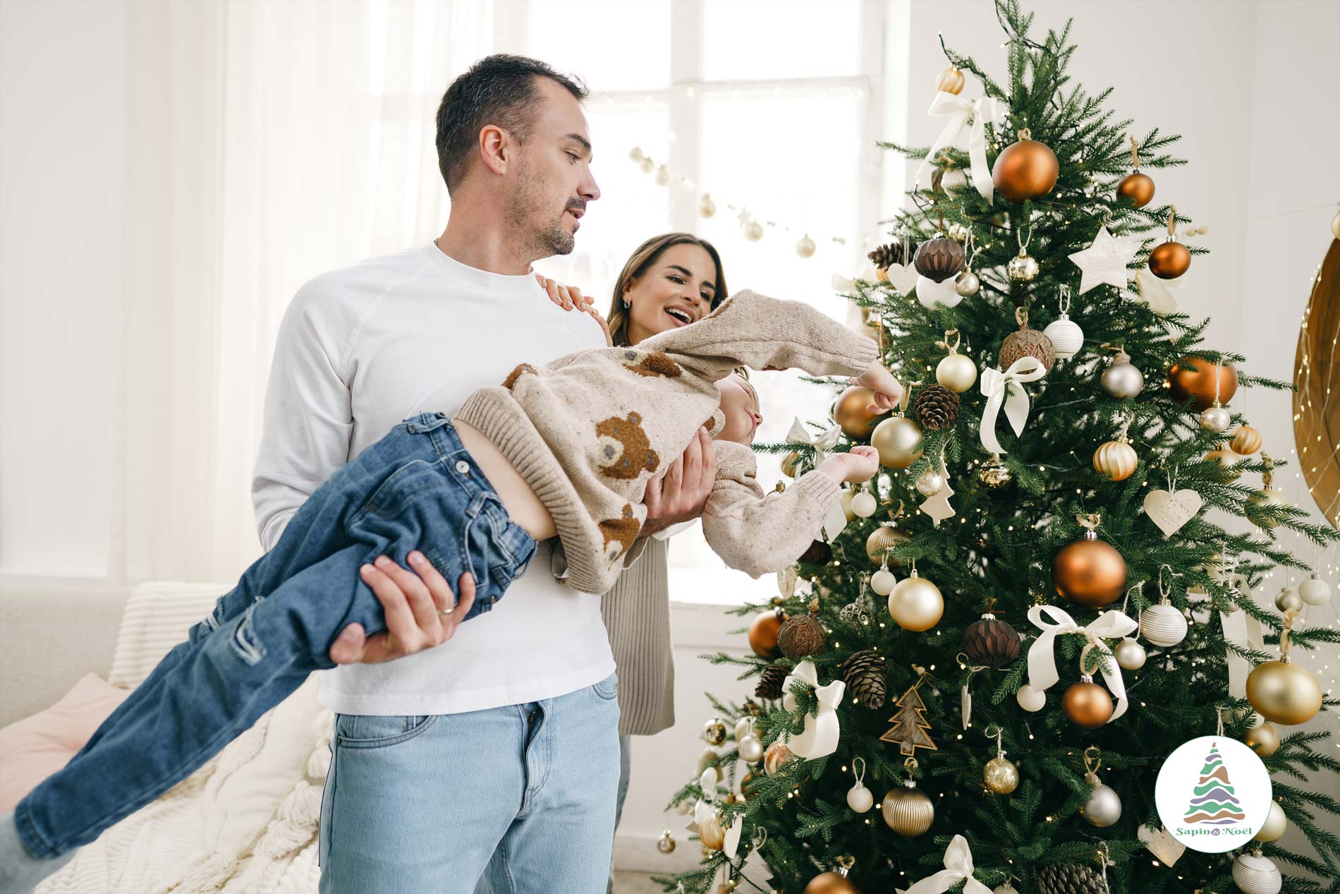 Un enfant dans les bras de son père décore un sapin de Noël